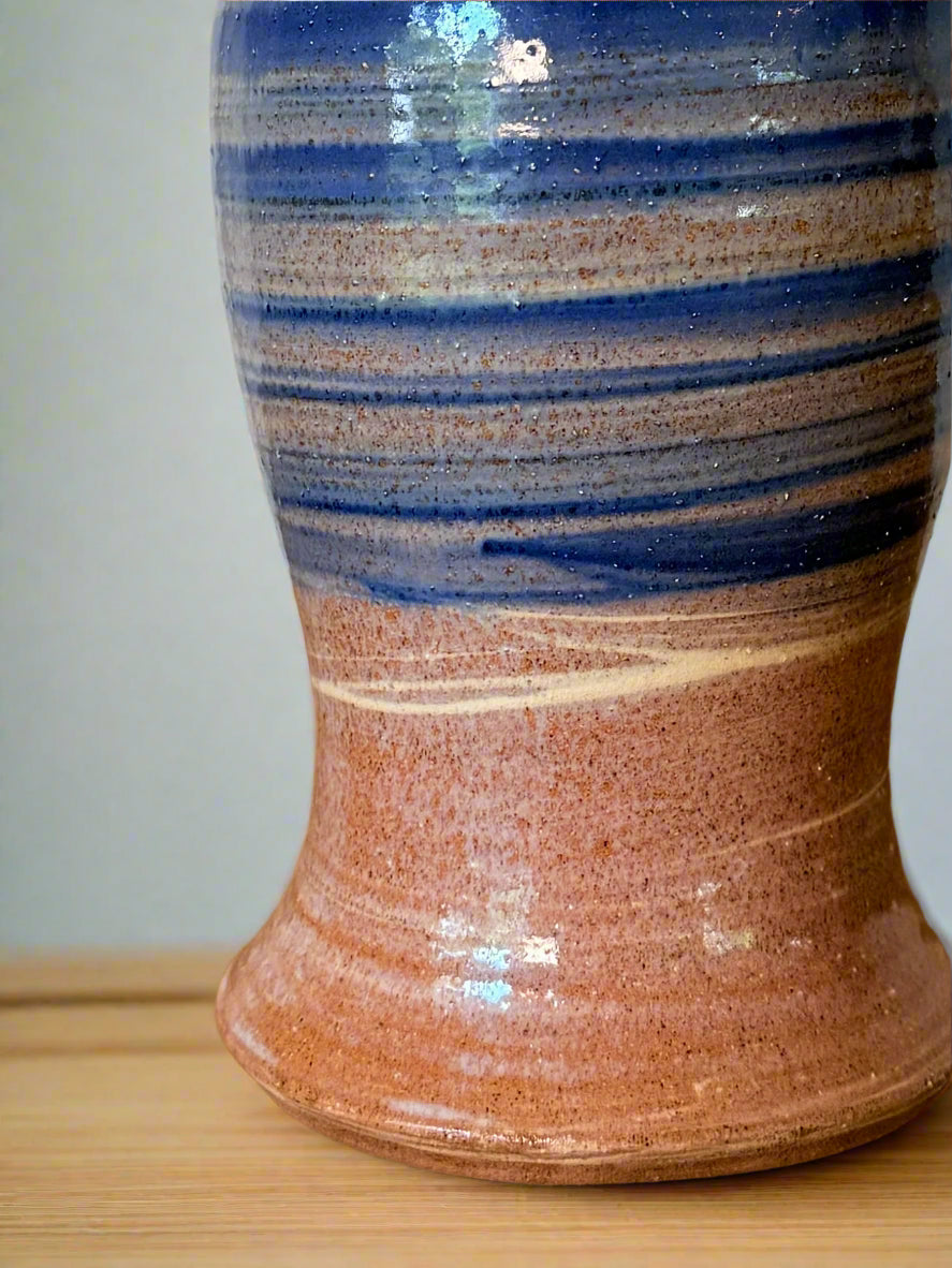 Ceramic vase with blue and brown stripes on a wooden surface